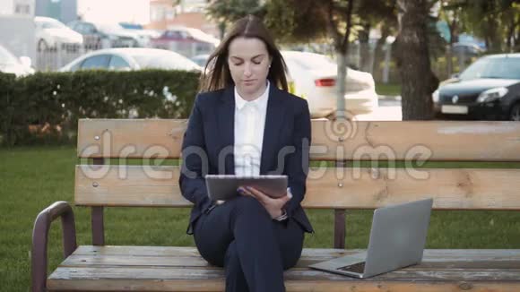 年轻漂亮的商务女性使用平板电脑坐在户外视频的预览图
