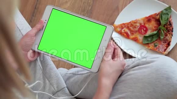 女人看着家里有绿色屏幕的平板电脑视频的预览图