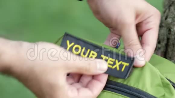 在绿色的背包上贴上一个补丁上面写着你的文字黑色背景上的黄色字母视频的预览图
