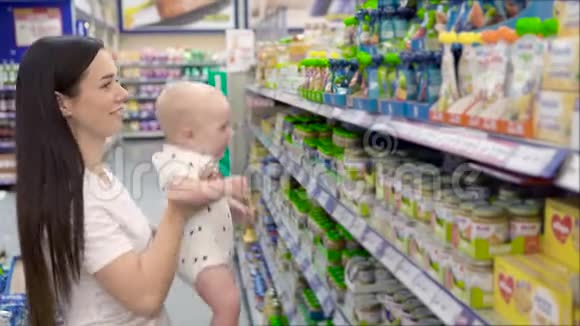 美丽的女人带着小儿子在超市购物年轻的母亲在市场上为孩子选择食物视频的预览图