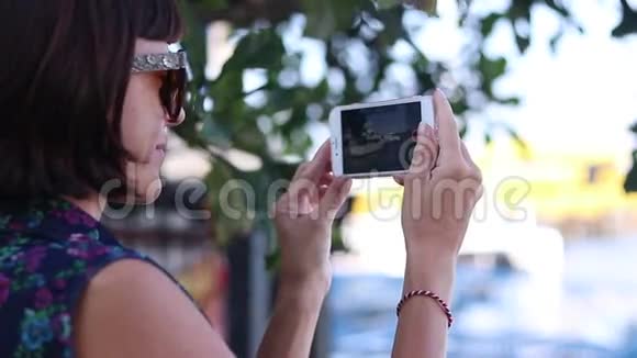 年轻女子在智能手机游艇和海洋上拍摄视频特写镜头戴眼镜的年轻女人用智能手机视频的预览图