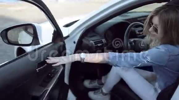 穿牛仔裤的漂亮女孩从车里爬出来休闲风格视频的预览图