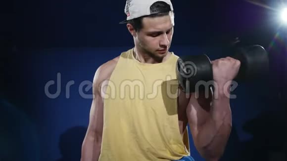 年轻肌肉发达的运动员在健身房锻炼坐在举重机上举起两个哑铃视频的预览图