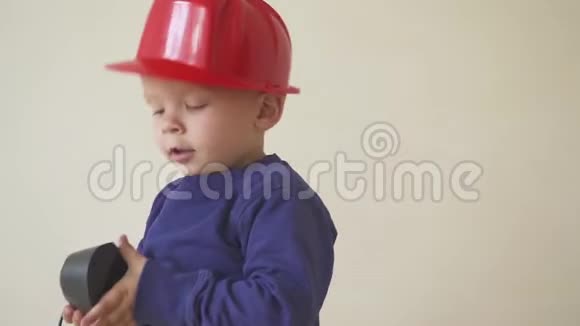 年轻可爱的建筑男孩穿着制服戴着安全帽或头盔在电动螺丝刀的背景下视频的预览图