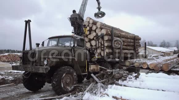 在锯木厂生产时卡车爪式装载机从重型卡车上卸下木材视频的预览图