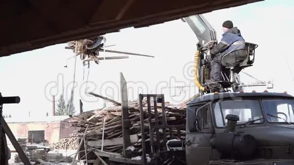 起重机爪式装载机在锯木厂设施从重型卡车上卸下木材废料视频的预览图