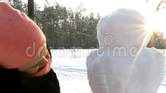 这个女孩冬天在树林里堆雪人从后面看到的视频的预览图