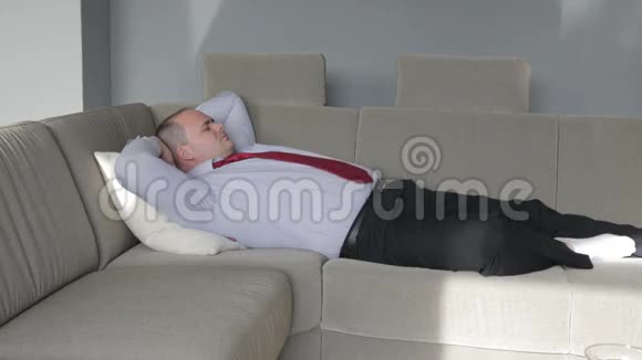 商人躺在客厅的沙发上试图睡觉视频的预览图