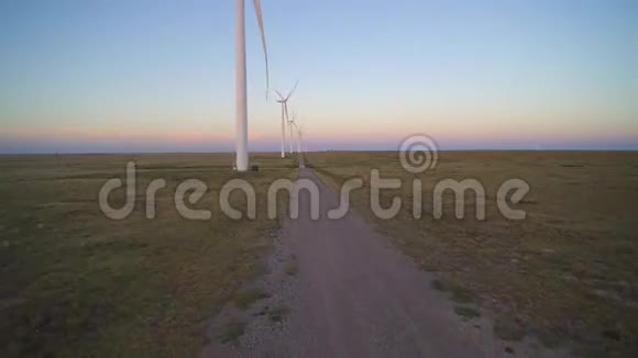 傍晚日落时分在一片大片土地上用4k空中拍摄了巨大的白色风力涡轮机视频的预览图