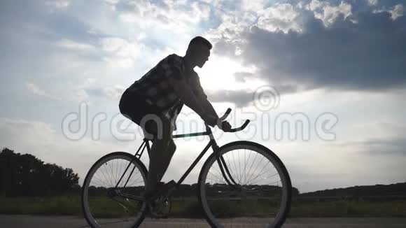 年轻男子骑着老式自行车的剪影背景是美丽的天空骑自行车的人视频的预览图