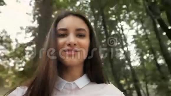 自拍女孩的概念年轻漂亮快乐的学生模特微笑着在公园里散步视频的预览图