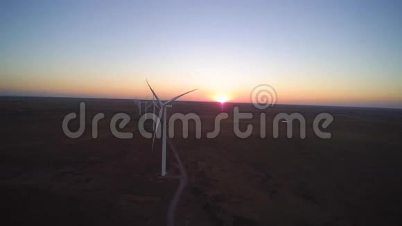 大白风力涡轮机在草原田野美丽的傍晚日落4k鸟瞰视频的预览图