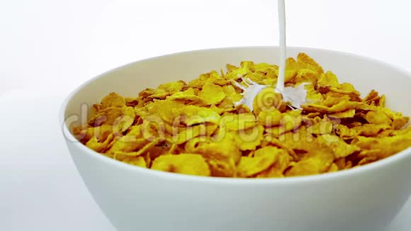 谷物玉米片在倒入牛奶的碗中掉落在白色背景下缓慢运动饮食健康食品的概念视频的预览图