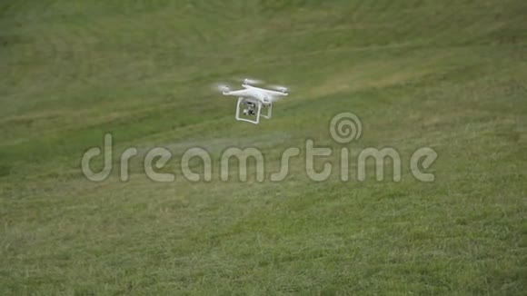 白色无人机四架飞机在草地背景下的蓝天上飞行视频的预览图