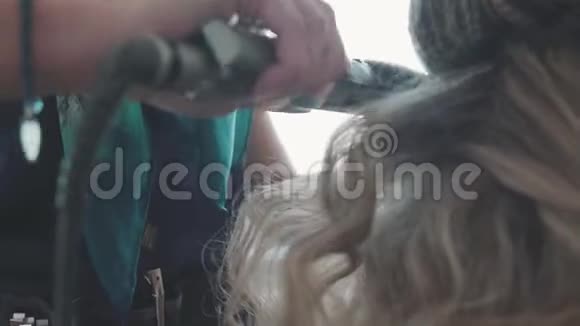 发型师为一个女孩做发型卷发头发的热保护视频的预览图