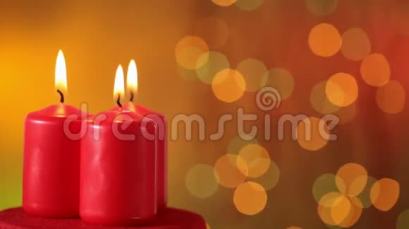 三支圣诞蜡烛在模糊的圣诞灯光前燃烧和旋转视频的预览图