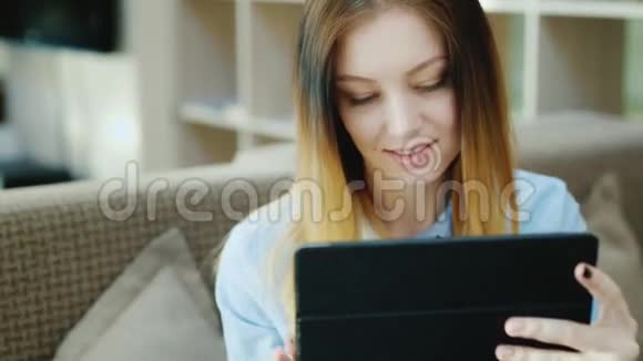 一位年轻迷人的女士在咖啡馆里享受着平板电脑的肖像视频的预览图