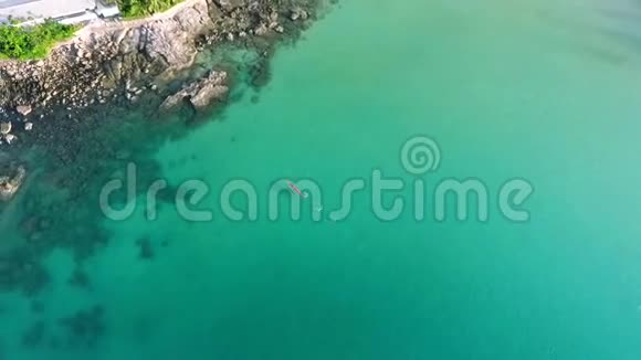 运动员在靠近岩石的蓝色水中的长皮艇上游泳高清鸟瞰图泰国普吉岛视频的预览图