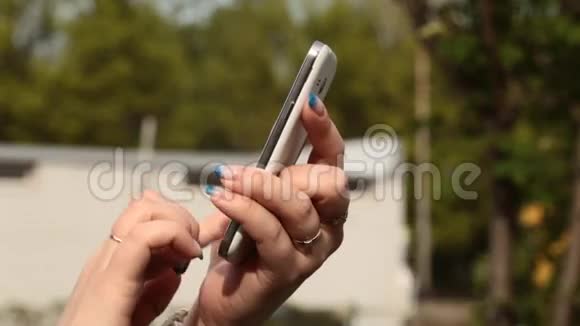 在户外使用智能手机的年轻女性写SMS或电子邮件视频的预览图