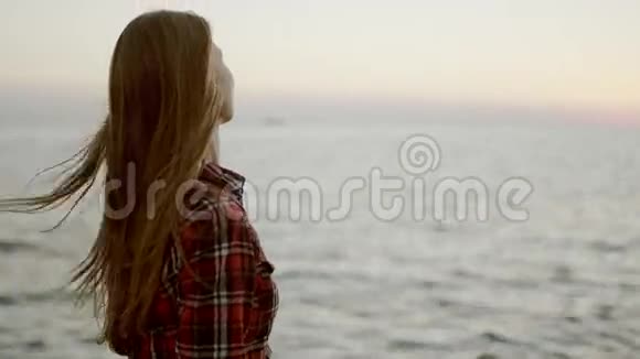 一个年轻女孩坐在海边看地平线视频的预览图