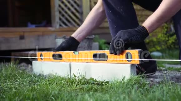 工人把瓷砖放在花园里用水平工具把它放在水平上4K视频的预览图