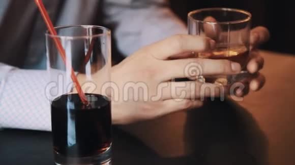 穿格子衬衫的人手拿着一杯威士忌在咖啡馆的桌子上视频的预览图