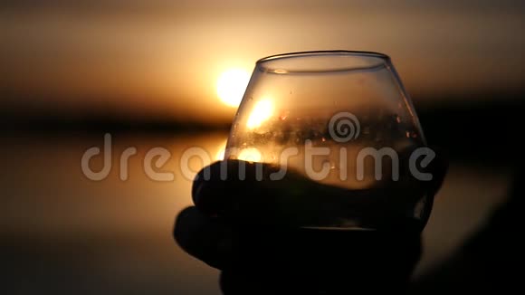 两杯酒杯在美丽的金色夕阳的背景下喝着美味的饮料慢动作1920x1080全高清视频的预览图