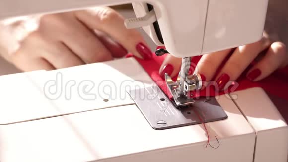 女人用现代缝纫机缝纫在机器上缝纫时支撑羊毛布的手红色布料a视频的预览图