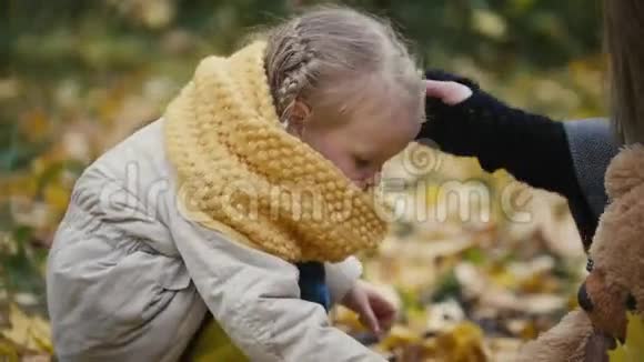 小金发女孩和妈妈在秋季公园收集树叶关门视频的预览图