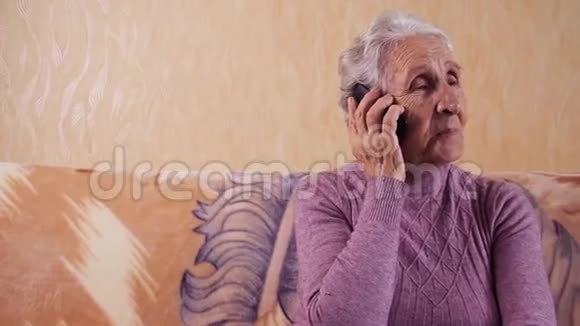 一位坐在沙发上用手机说话的老年妇女他通过手机智能手机进行交流视频的预览图