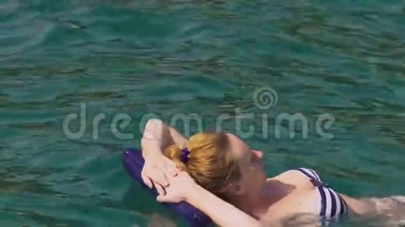 一个没有化妆的女人休息一个女孩躺在充气枕头上漂浮在海里4K慢动作视频的预览图