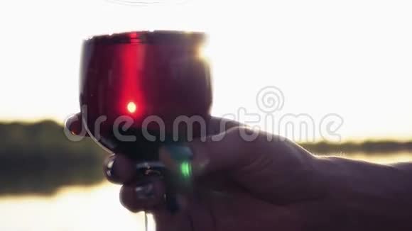 一杯红酒在阳光的照射下在酒杯周围溅起捕捉到夕阳的光芒特写镜头慢慢视频的预览图