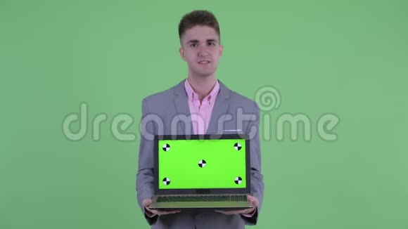 快乐的年轻商人一边说话一边展示笔记本电脑视频的预览图