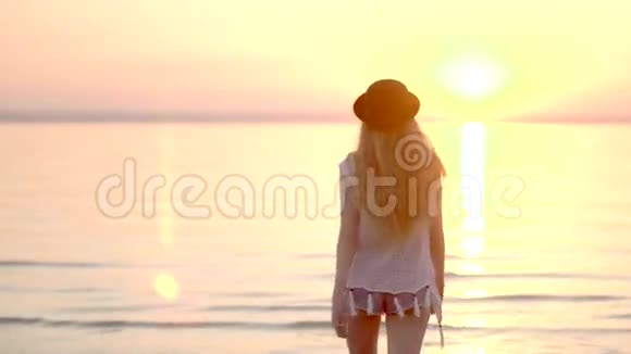 年轻女子走在海边享受大自然和日落视频的预览图