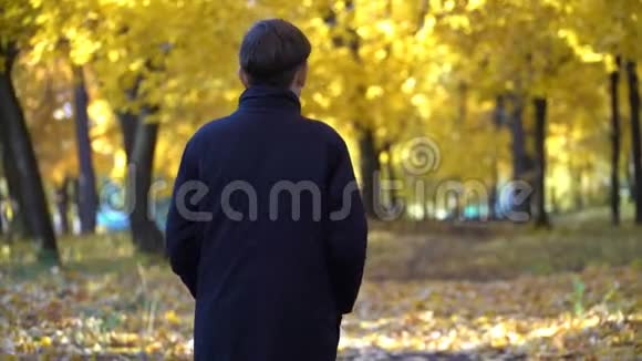 秋天公园里穿黑色外套的年轻人视频的预览图