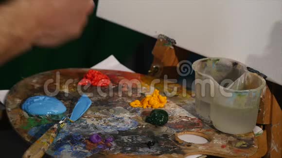 艺术家的手把颜料从管子挤到调色板上特写视频的预览图