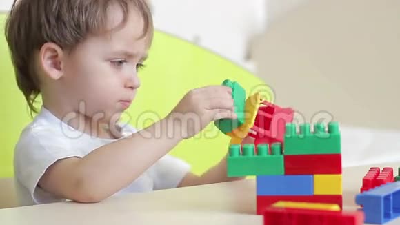 男孩用桌子上的彩色积木盖房子视频的预览图