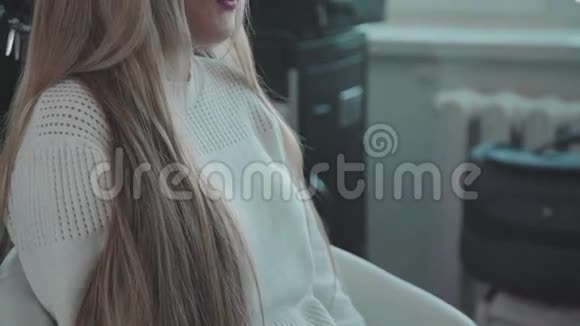 年轻的金发女郎穿着白色毛衣来到美容院视频的预览图