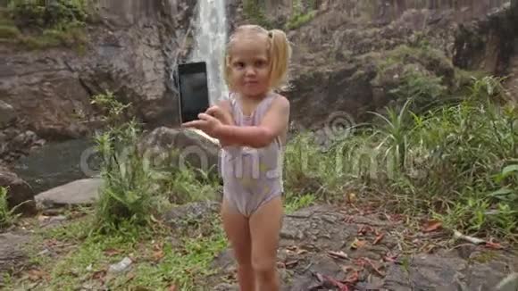 穿泳装的贴身小女孩让自拍对抗瀑布视频的预览图