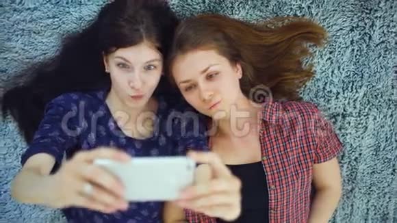 两个穿着睡衣的漂亮女孩在家里卧室的床上自拍肖像的俯视图视频的预览图