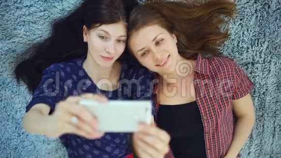两个穿着睡衣的漂亮女孩在家里卧室的床上自拍肖像的俯视图视频的预览图
