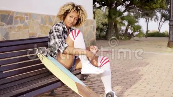 年轻女子在长凳上系滑板鞋视频的预览图