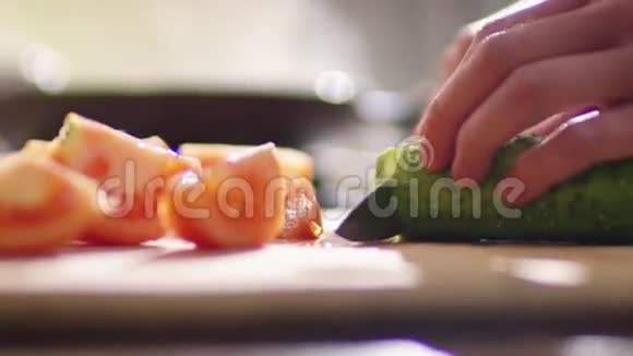一个女孩正在厨房里做沙拉这个女孩已经切了红番茄现在她正在切绿多汁的番茄视频的预览图