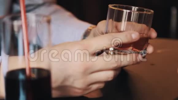 男人在和女人说话的时候双手翻着一杯威士忌视频的预览图