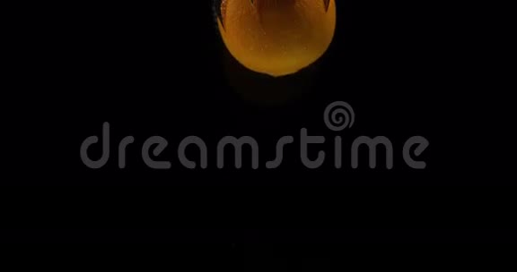 橙柑橘黑背景下落入水中的果实视频的预览图