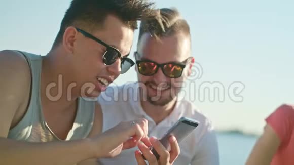 在海滩上玩电话的年轻人视频的预览图