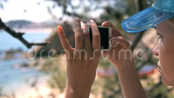 美丽的女人在天堂岛的海滩上使用她的手机视频的预览图