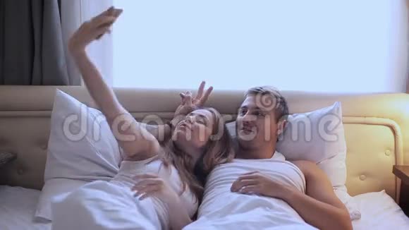男人和女人在床上自拍一个女孩和一个男人在前摄像头上给自己拍照视频的预览图