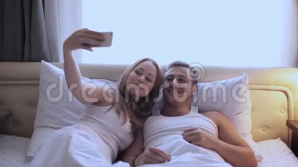 男人和女人在床上自拍一个女孩和一个男人在前摄像头上给自己拍照视频的预览图