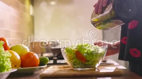 穿睡衣的年轻漂亮女孩正在厨房做饭她做了一些新鲜的沙拉配上青莴苣黄瓜和视频的预览图